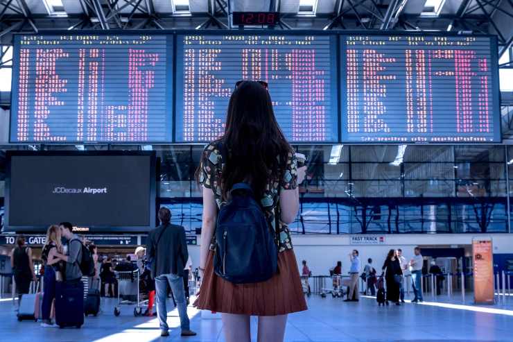 donna in aeroporto che legge gli orari sul tabellone