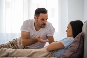 Uomo che discute con donna arrabbiata, a letto